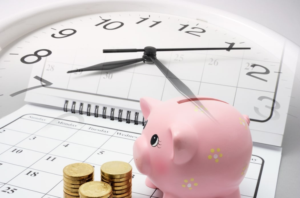 대출 중도상환 관련 시계 위에 달력과 돼지저금통, 동전이 놓여진 모습