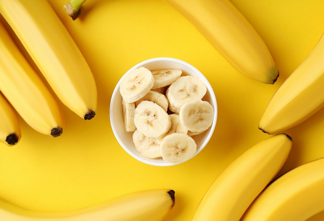 바나나 칼로리 관련 썰려 있는 바나나가 그릇에 담겨져 있고 주변에 바나나가 놓여진 모습